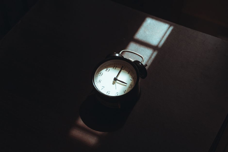 A nostalgic analog clock in moody shadows, capturing serene morning light.