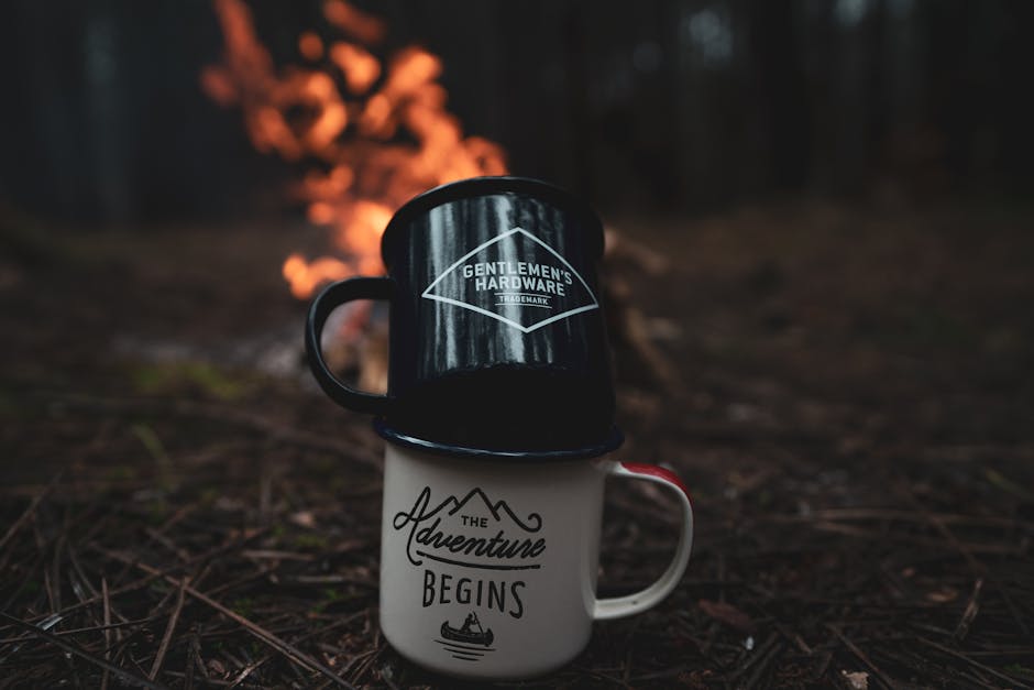 Two metal mugs stacked near a campfire in a dark forest, perfect for an adventurous outdoor vibe.