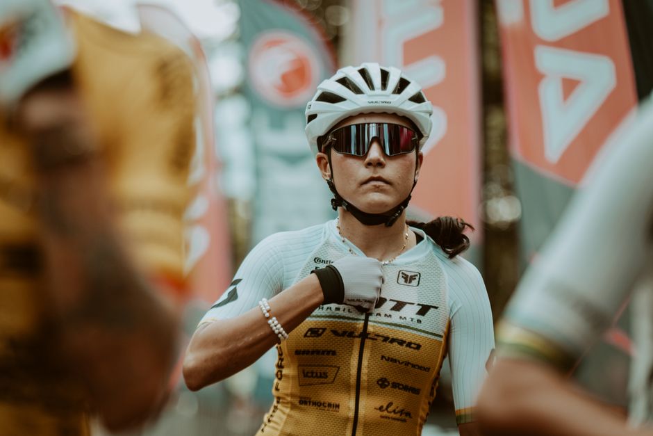 A determined cyclist adjusts her gear, preparing for a race. Captured in a vibrant outdoor
