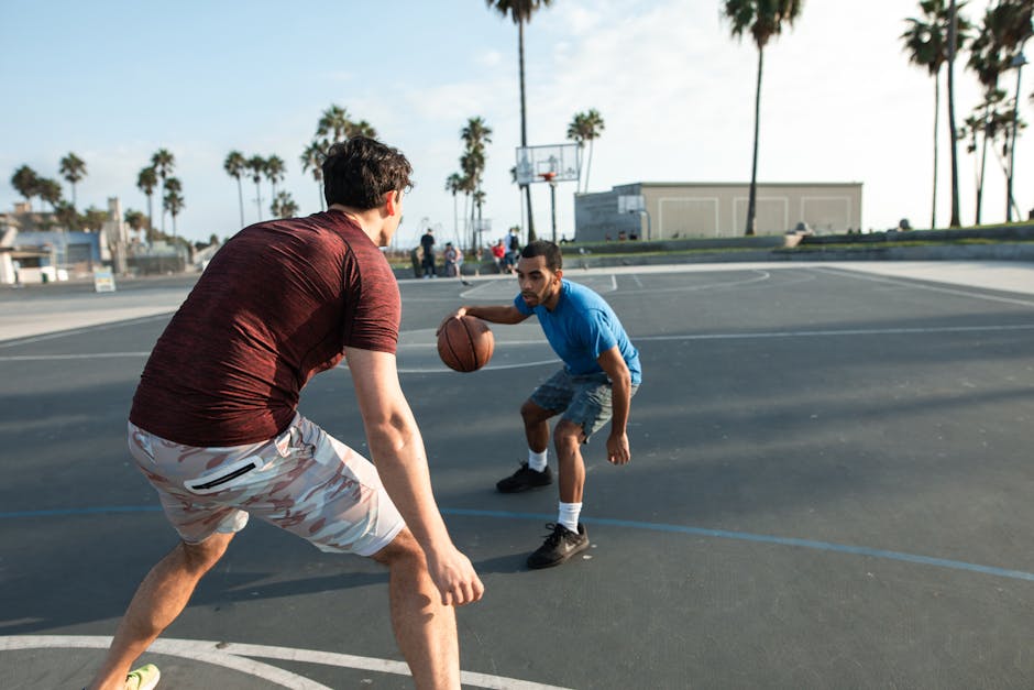Determined young multiethnic men wearing sportive clothes playing basketball on sports ground in tropical country on sunny day
