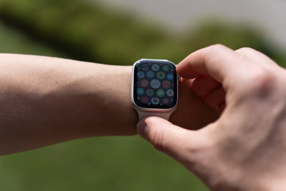 A close-up of a person's hand interacting with a smartwatch on their wrist, outdoors.