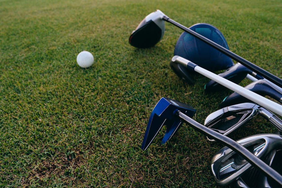 A close-up view of golf clubs and a golf ball on a lush green grass field.