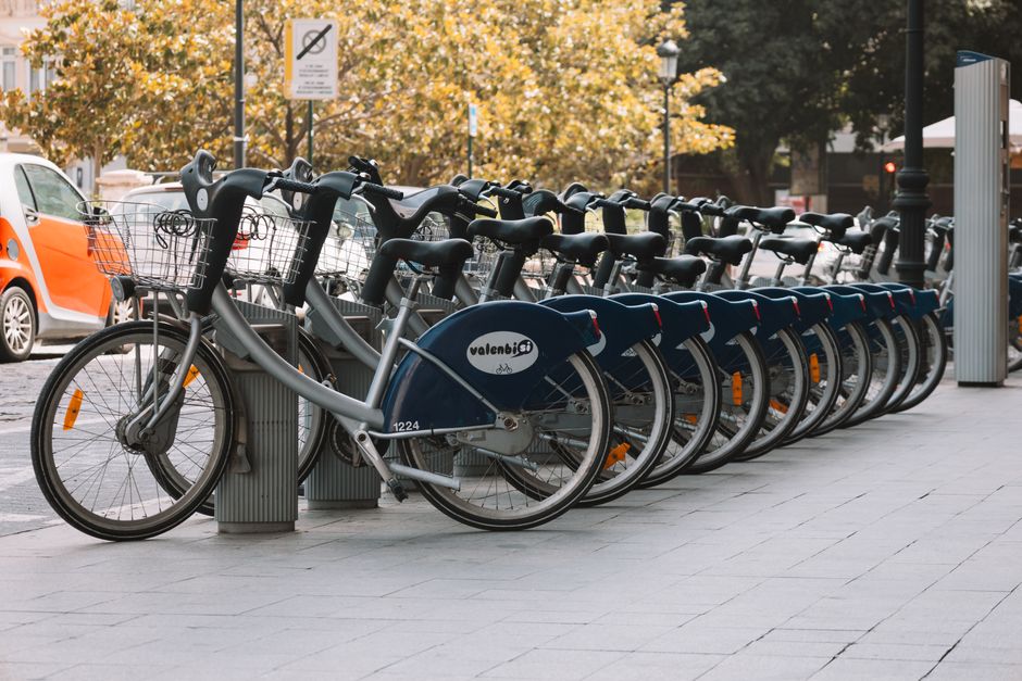 Multiple bicycles parked in a row at a public bike-sharing station in Valencia city center, ideal for urban transport.