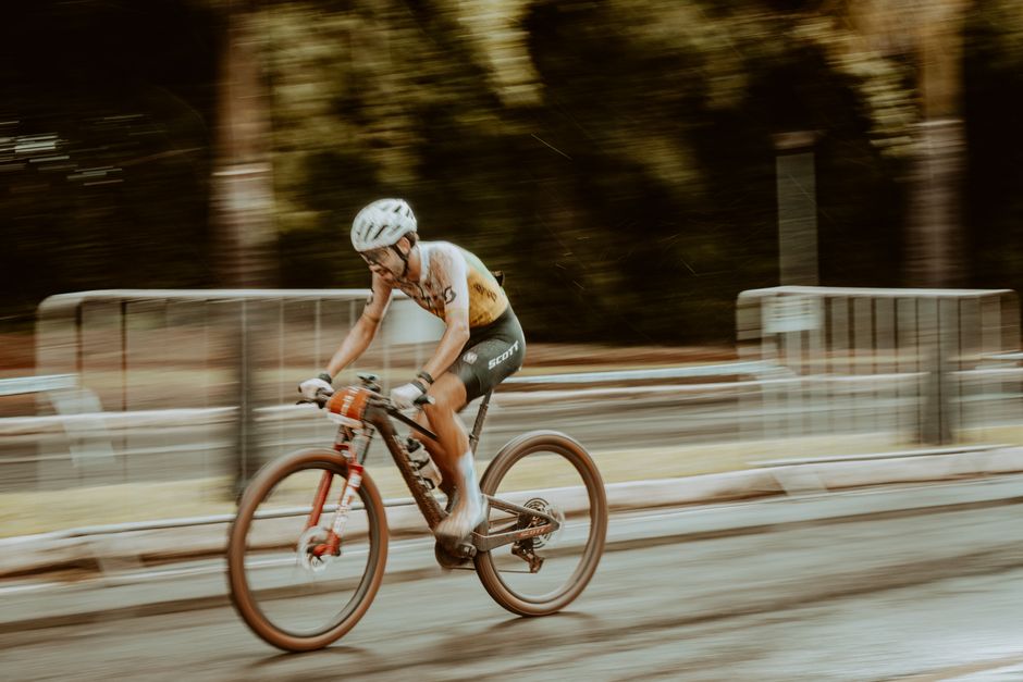 Blurred motion shot of a cyclist racing outdoors on a road.