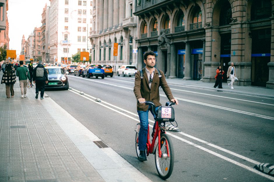 A man rides a bicycle in a busy city street, surrounded by historic architecture.