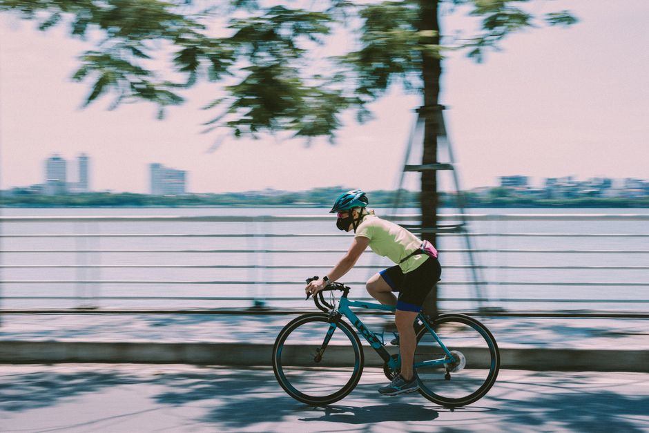 Cyclist in motion on a sunny day beside Hoan Kiem Lake, Vietnam.