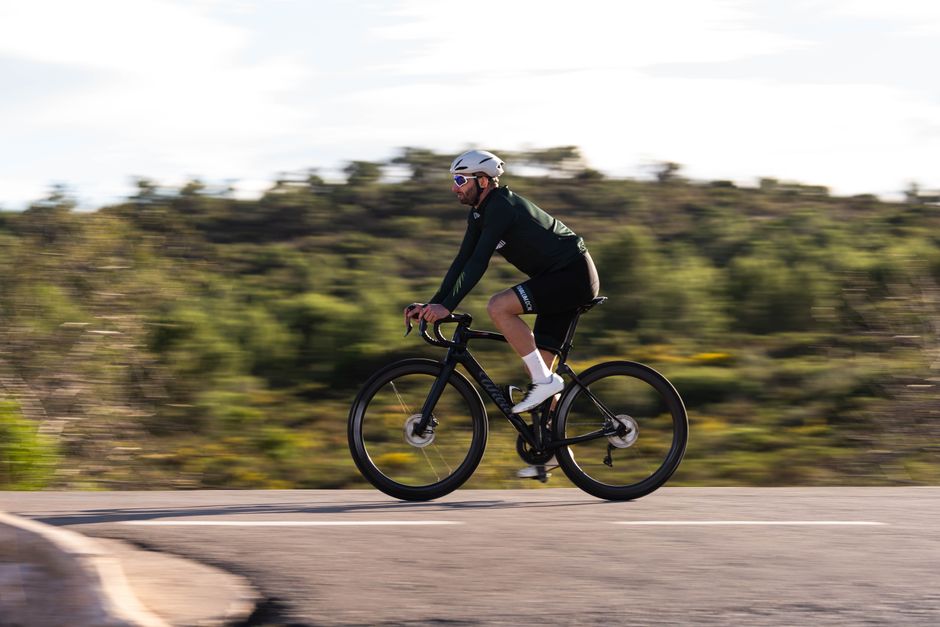 Cyclist riding a road bike in a scenic outdoor location, wearing sportswear and helmet.