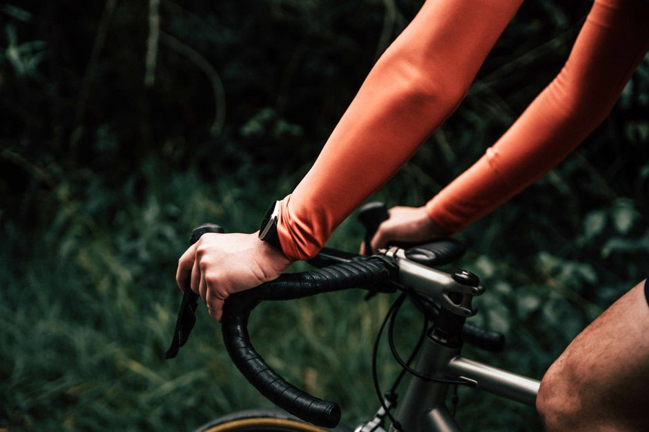 Cyclist's hands gripping handlebar during outdoor ride, wearing sportswear.