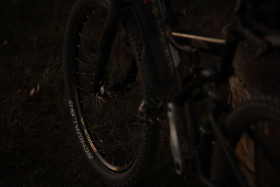 Dark, atmospheric close-up of a bicycle wheel captured in a moody setting.