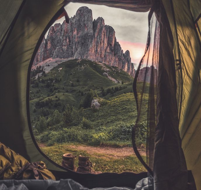 A breathtaking view of jagged mountains from a cozy tent during sunrise, perfect for adventurers.