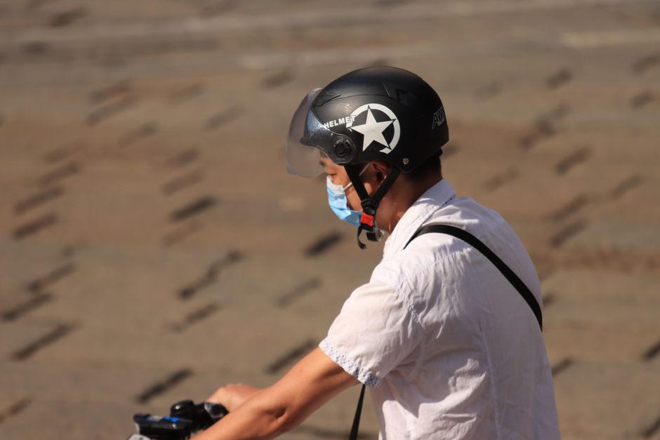 Side view of a man biking outdoors wearing a helmet and face mask for protection.