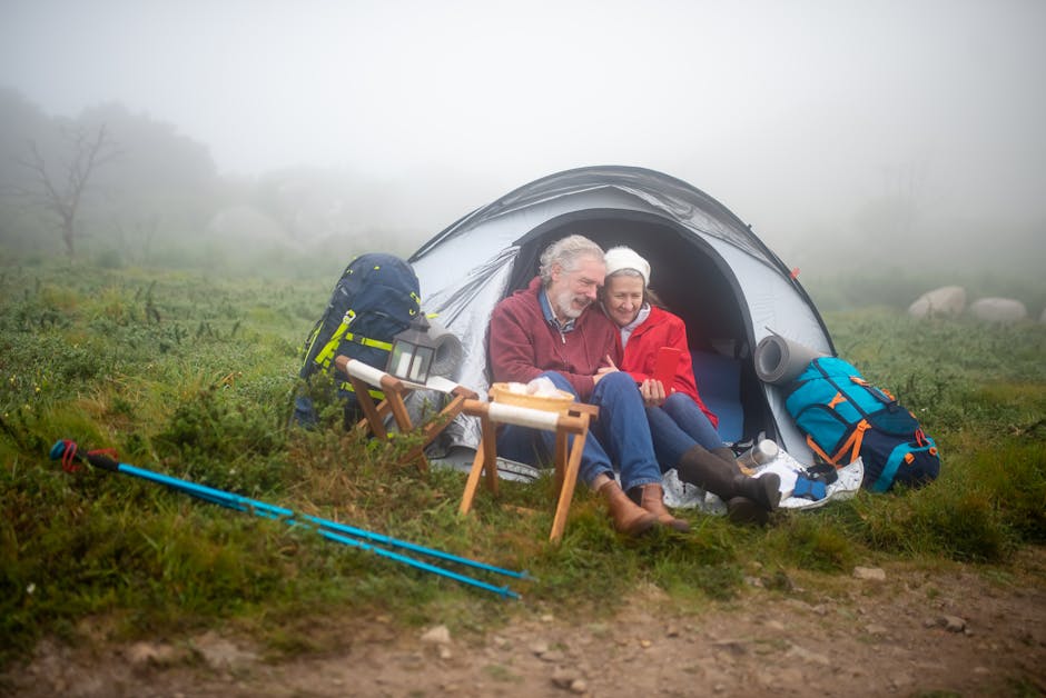 Elderly couple enjoys a cozy camping experience in a foggy Portuguese landscape, embracing nature and adventure.