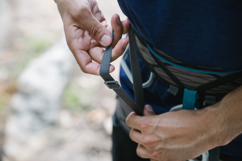 Detailed close-up of a person adjusting a safety harness, emphasizing the importance of safety while climbing.