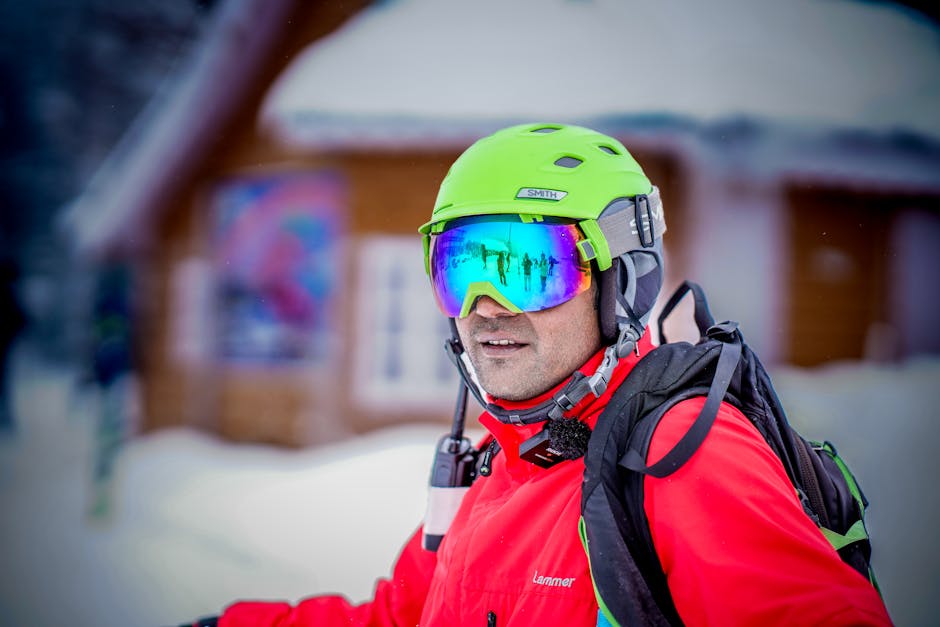 Adult skier wearing bright gear and reflective goggles, enjoying a snowy outdoor scene.