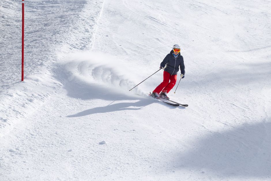 Action shot of a skier skillfully navigating a snowy slope on a sunny winter day.
