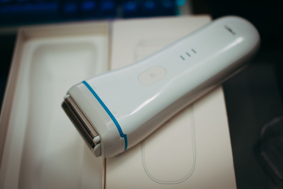White handheld electric shaver placed on its packaging, showcasing its sleek design and functionality.