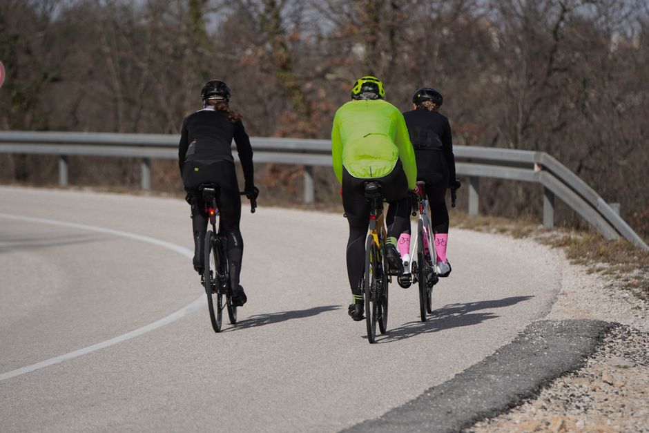 Cyclists enjoying a weekend ride on a curving countryside road during spring.