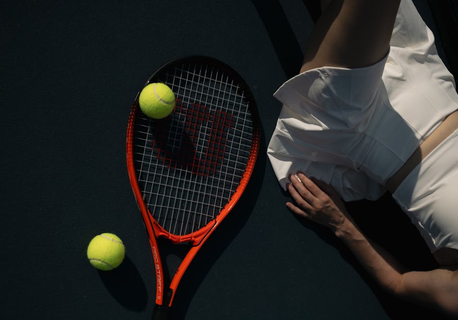 Tennis player in white sportswear next to racket and tennis balls on court.