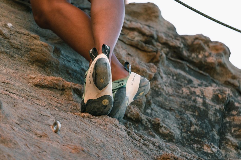 A close-up view of a climber's feet in climbing shoes clutching a rocky surface enhancing the thrill of climbing.