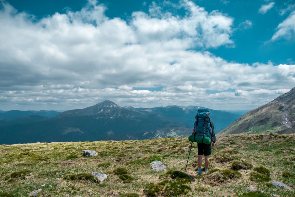 Backpacker exploring scenic Carpathian Mountains in Ukraine under a blue sky.