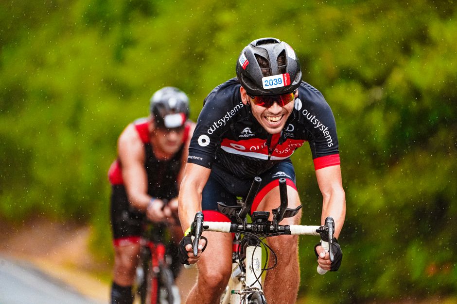Two cyclists compete intensely in a rainy outdoor race.