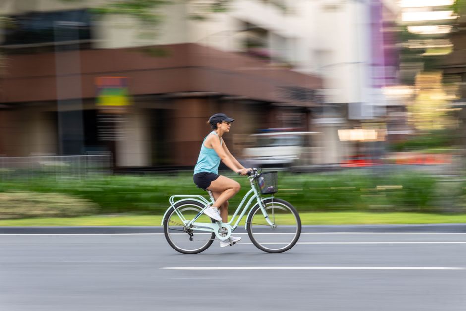 Woman bicycling quickly in an urban area, showcasing motion and vitality.