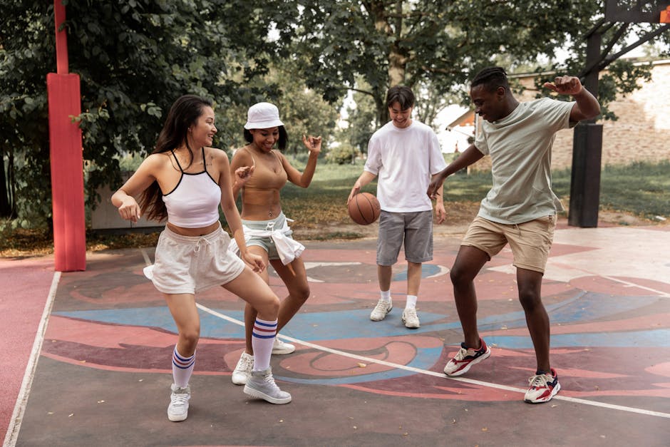 Group of young joyful multiracial friends wearing casual clothes dancing happily together on sports ground in summer park